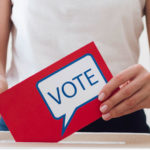 personne déposant un bulletin de vote dans une urne